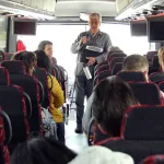 Ken Apacki talking to students on bus
